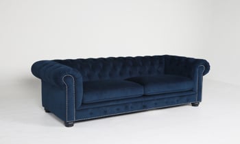 Traditional chesterfield armchair made with a dark blue velvet fabric.