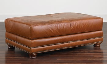 50-inch ottoman in cognac top-grain leather with nailhead trim and bun feet.